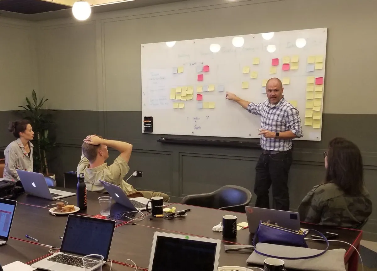 Eric leading a workshop at a whiteboard covered in sticky notes